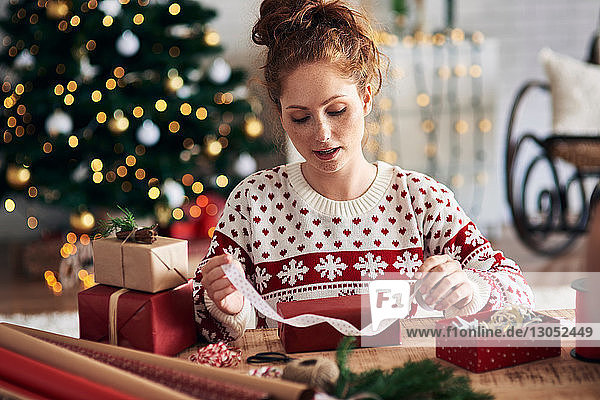 Frau bindet Schleife am Weihnachtsgeschenk
