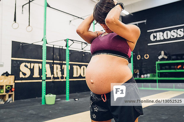 Pregnant woman holding head in hand in gym