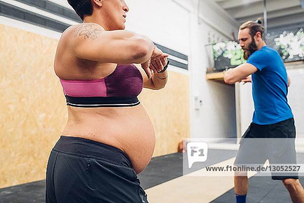 Schwangere Frau und Trainerin beim Aufwärmen im Fitnessstudio