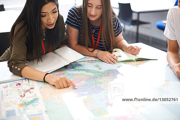 College students studying world map in classroom