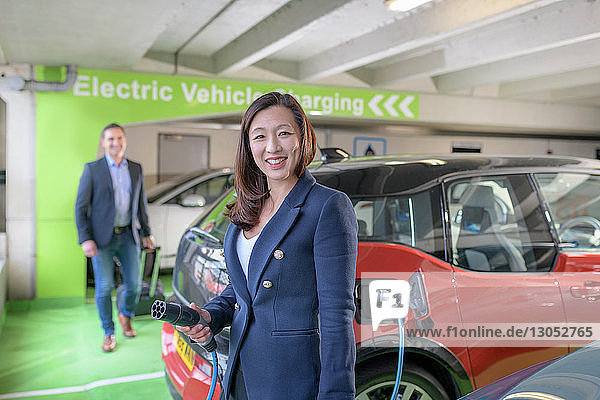 Man and woman charging electric car at charge bay Manchester UK