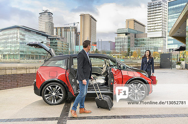 Man and woman with parked electric car Manchester UK