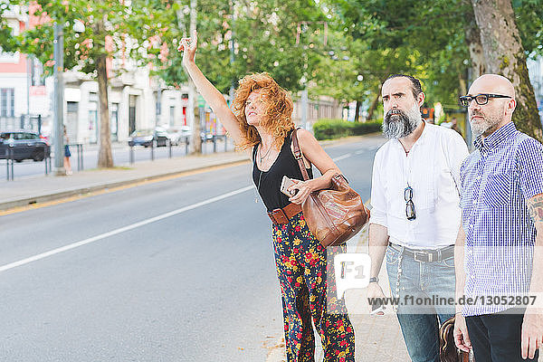 Mittelgroße erwachsene Frauen und männliche Freunde rufen ein Taxi auf der Straße in der Stadt