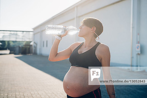 Schwangere Frau trinkt während des Trainings