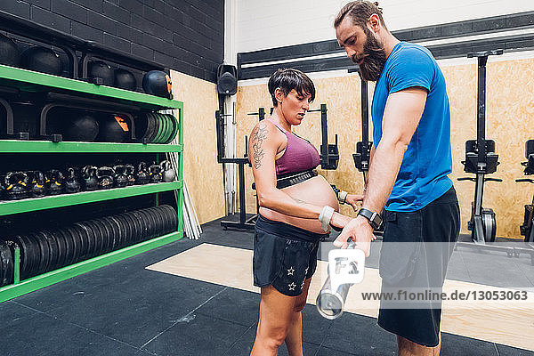 Schwangere Frau benutzt Barglocke im Fitnessstudio