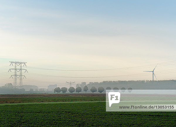 Landschaft mit Windturbine und Stromleitungen an einem nebligen Morgen  Niederlande