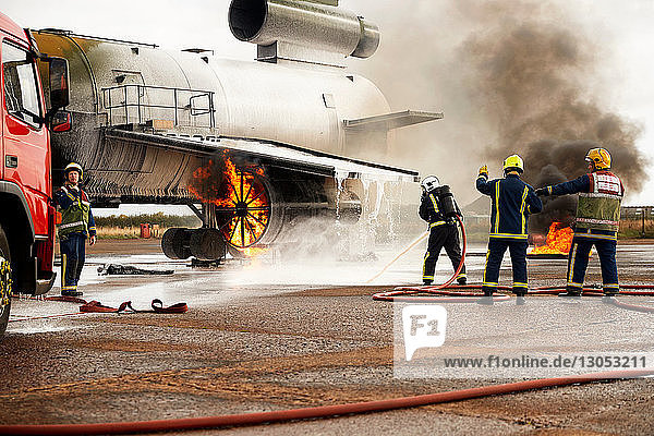 Firemen training  spraying water at mock airplane engine