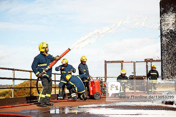 Ausbildung von Feuerwehrleuten  Feuerwehrmänner sprühen Feuerlöschschaum in der Ausbildungsstätte