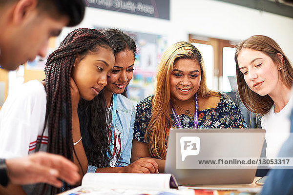 Hochschulstudentinnen und -studenten schauen im College-Klassenzimmer auf den Laptop