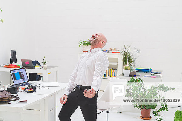 Crazy businessman playing air guitar in office