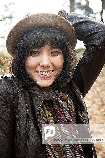 Portrait of happy woman wearing hat while standing on field