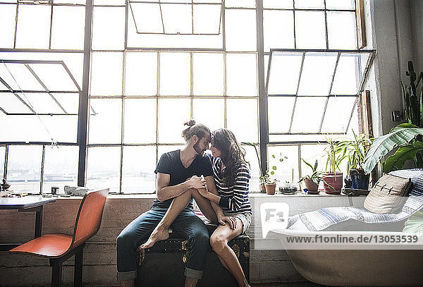 Young couple relaxing against window at home