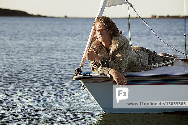 Mann betrachtet Aussicht  während er sich auf einem Segelboot entspannt