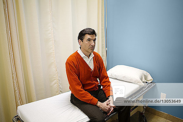 Mann sitzt auf Krankenhausbahre