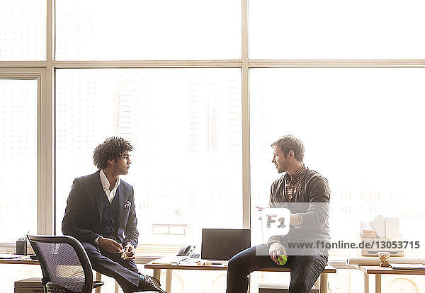 Geschäftsleute diskutieren  während sie im Büro am Tisch sitzen