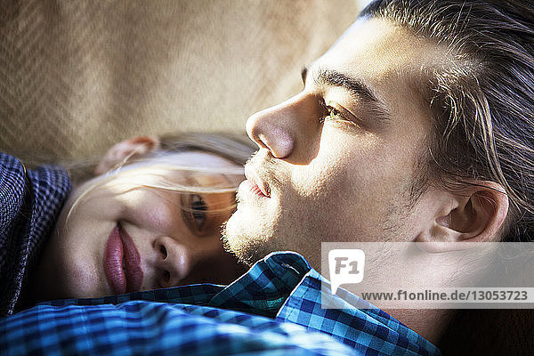 Portrait of happy woman lying on man at home