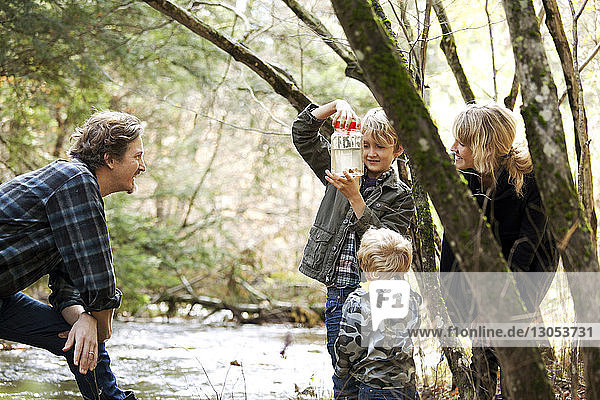 Family looking at scorpions in jar while standing by river