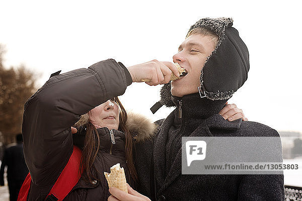 Girlfriend feeding ice cream man in park