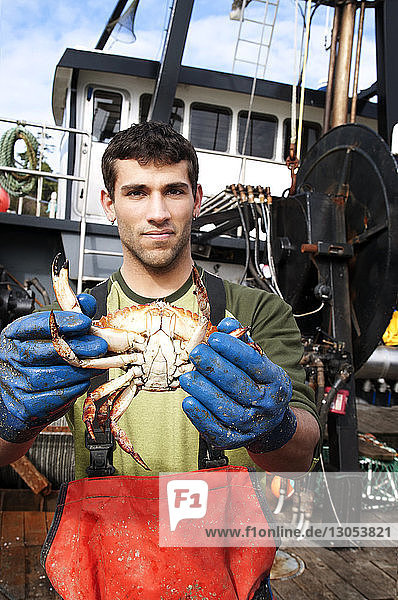 Portrait of fisherman holding crab and standing on boat