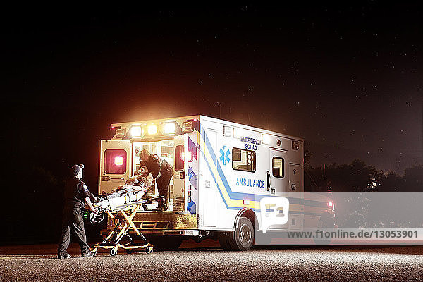 Sanitäter heben Patienten nachts im Krankenwagen