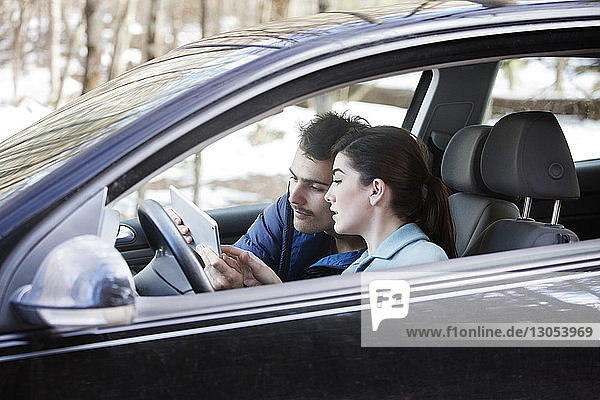 Paar benutzt Tablet-Computer  während es im Auto sitzt