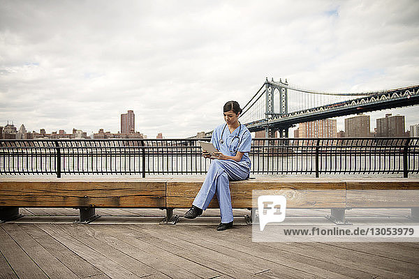 Ärztin sitzt auf Bank gegen Manhattan-Brücke in der Stadt