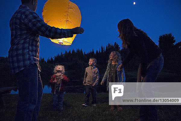 Low angle view of happy family with illuminated lantern at field