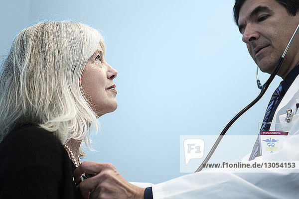 Doctor examining patient with stethoscope in hospital