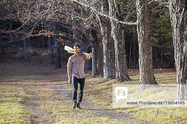 Mann mit Rudern in voller Länge beim Gehen auf einem Feld im Wald