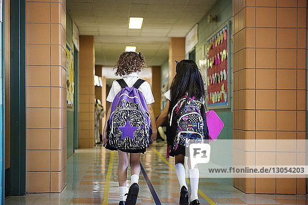 Rear view of schoolgirls walking in corridor