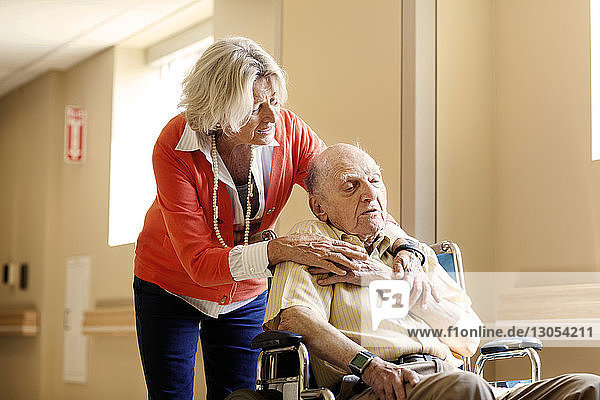 Besorgte Frau mit älterem Mann auf Rollstuhl im Krankenhaus