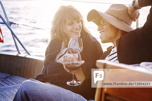 Couple drinking red wine while sitting on yacht