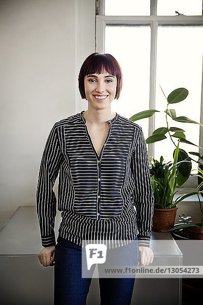 Portrait of happy confident woman standing in creative office