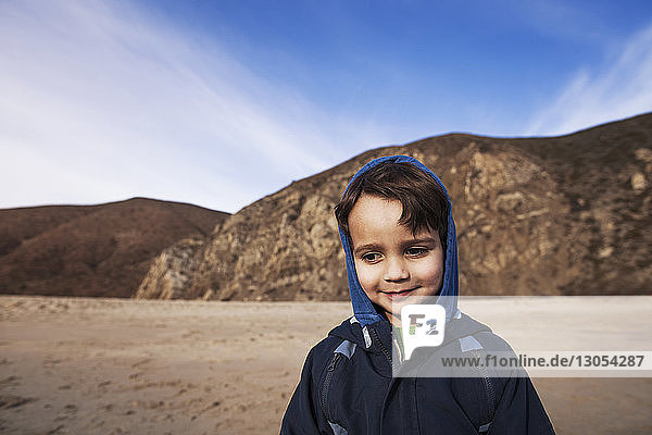 Boy smiling while standing on shore at beach