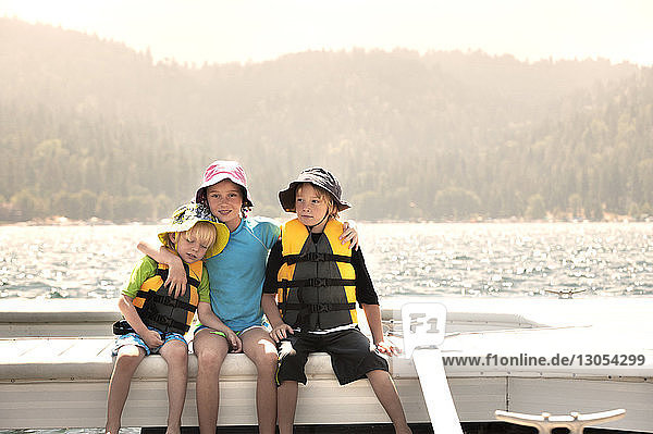 Portrait of sister with brothers traveling on boat against sky