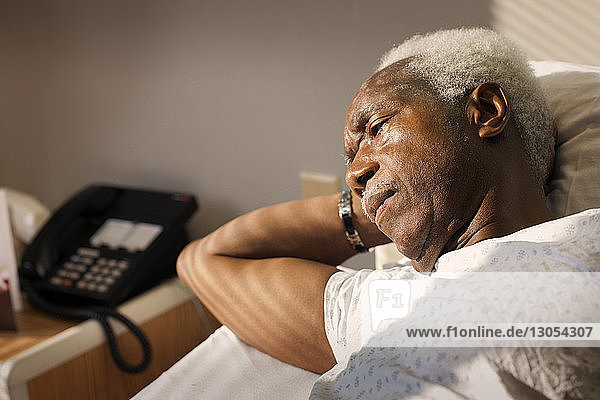 High angle view of thoughtful man lying on bed in hospital