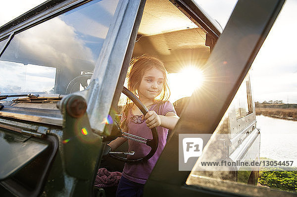 Girl sitting on driver's seat during sunny day