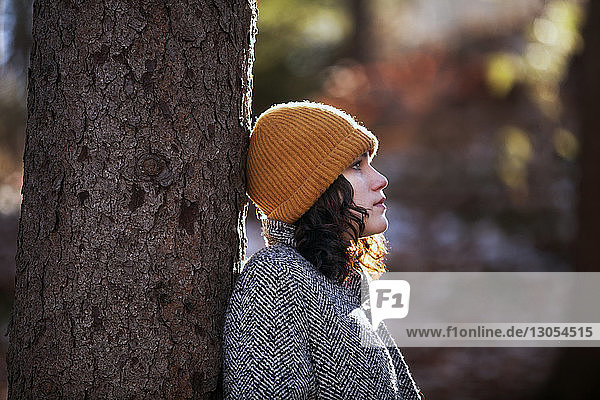 Seitenansicht eines jugendlichen Mädchens  das an Bäumen im Wald steht