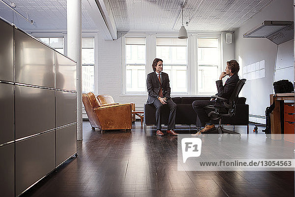 Businessmen discussing while sitting in office