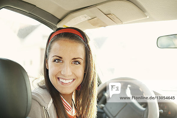 Porträt einer lächelnden Frau  die an einem sonnigen Tag im Auto sitzt