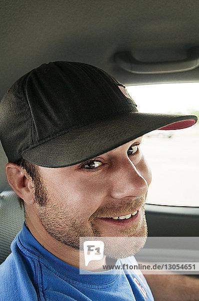 Portrait of smiling man wearing cap while traveling in car