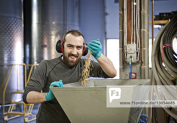 Porträt eines Mannes  der Gerste in Maschinen in der Destillerie fallen lässt