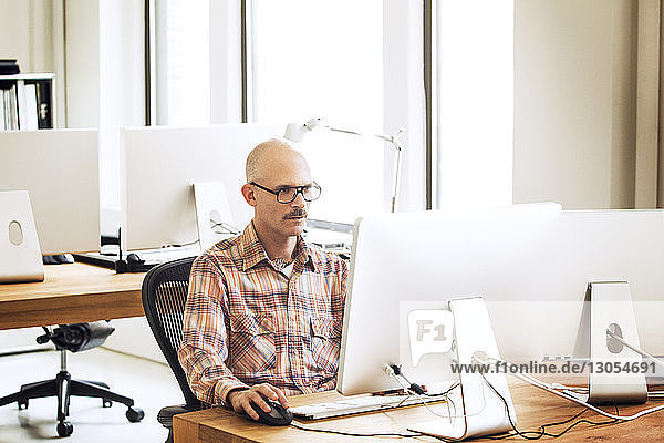 Man working on computer while sitting on chair in office