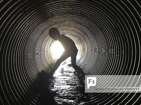 Scherenschnitt Junge steht im Abwassertunnel