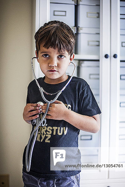 Junge schaut weg  während er zu Hause ein Stethoskop benutzt