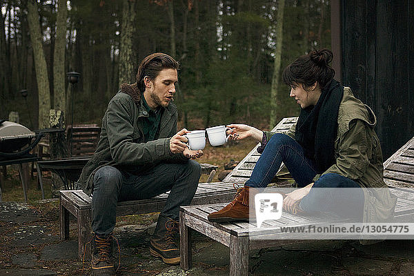 Ein Paar röstet Kaffeetassen  während es auf einem Liegestuhl auf dem Campingplatz sitzt