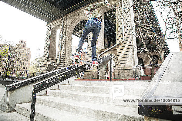 Mann fährt Skateboard auf Geländer an Stufen