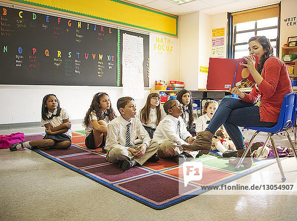 Teacher showing picture book to students in classroom