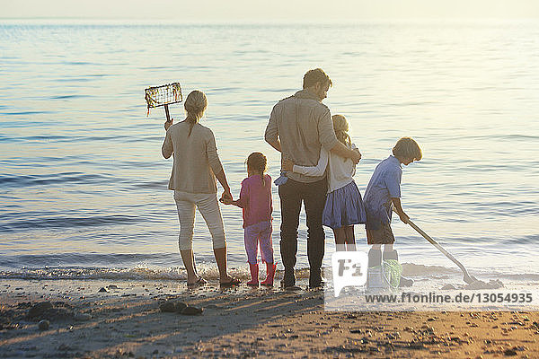 Familie reinigt Strand bei Sonnenuntergang