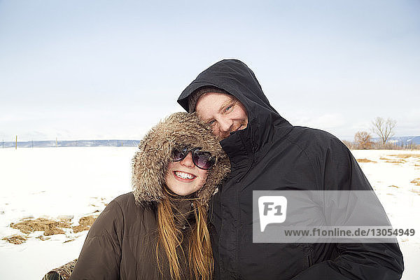 Porträt eines Ehepaares auf verschneitem Feld vor klarem Himmel